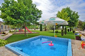 a swimming pool with an umbrella next to a playground at Di Mare Holiday Village in Kranevo