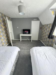 a bedroom with two beds and a tv in it at Families and Contractors Dudley DY1 in Lower Gornal