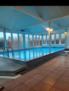 a large swimming pool in a building with windows at Ferienwohnung Kleine Kegelrobbe (mit Pool) in Burhave