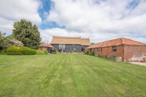 a large grass field in front of a building at Granary Cottage Valley Farm Barns, Snape in Saxmundham
