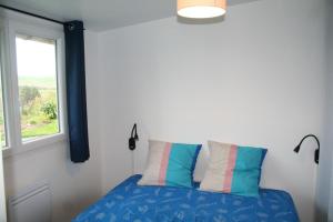une chambre avec un lit bleu avec une fenêtre dans l'établissement Le Randodo, à Quiberville