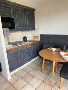 a kitchen with black cabinets and a wooden table at Appartement Le Beach du Lac d'Annecy avec les pieds dans l eau, plage et ponton privé in Duingt