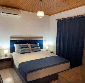 a bedroom with a large bed with blue curtains at Villa Alva in Sikia