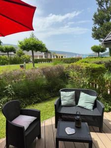 a patio with two chairs and a table with an umbrella at Appartement Le Beach du Lac d'Annecy avec les pieds dans l eau, plage et ponton privé in Duingt
