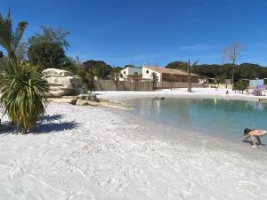 a woman is playing in the water on the beach at Camping Valras plage 5 étoiles in Vendres-Plage