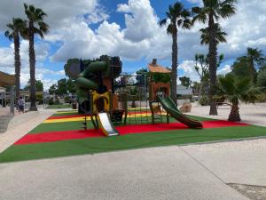 a playground with a slide in a park with palm trees at Camping Valras plage 5 étoiles in Vendres-Plage