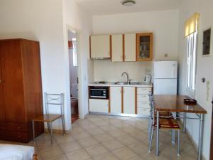 a kitchen with white cabinets and a table and a sink at Emmanouil in Kythira