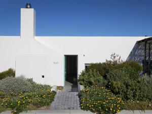 a white building with a black door and some flowers at The Cottage Collection Paternoster in Paternoster