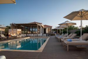 - une piscine avec des chaises et des parasols à côté d'un bâtiment dans l'établissement Elafonisos Resort, à Elafonisos