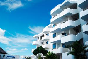 un edificio blanco con palmeras frente a un cielo azul en Escapaditas a la Playa, en Tonsupa