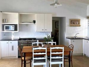 a kitchen with a wooden table and white cabinets at The Cottage Collection Paternoster in Paternoster