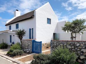 a white house with a blue fence in front of it at The Cottage Collection Paternoster in Paternoster