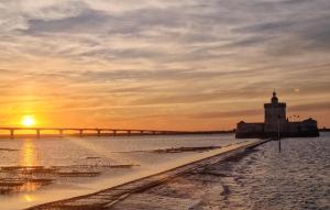 ein Leuchtturm und eine Brücke im Wasser bei Sonnenuntergang in der Unterkunft 1 Bedroom Awesome Apartment In Royan in Royan + 16 Fotos