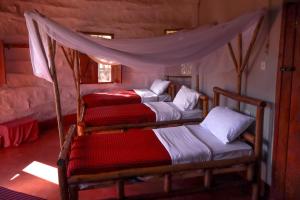 a bedroom with three bunk beds in a room at Maasai Eco Boma & Lodge - Experience Maasai Culture in Makuyuni