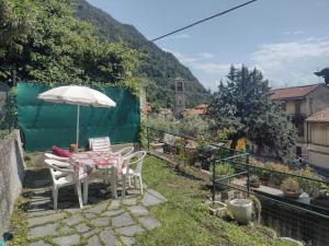 a table and chairs with an umbrella in a garden at Casa Argegno in Argegno