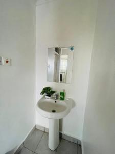 a white bathroom with a sink and a mirror at Bella Homes Thika Town in Thika