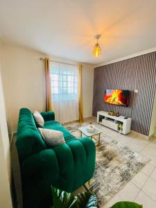 a living room with a green couch and a tv at Bella Homes Thika Town in Thika