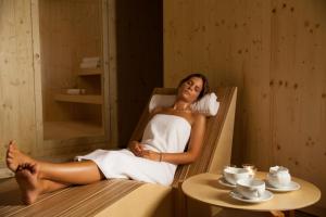 a woman sitting in a towel in a sauna at Colmeal Countryside Hotel in Figueira de Castelo Rodrigo