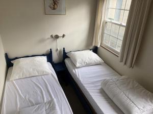 twee eenpersoonsbedden in een kamer met een raam bij Kustverhuur, Groede, Paarlhof 29 in Groede