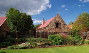 a stone house with a red roof in a yard at Delagoa Cottage Dullstroom in Dullstroom