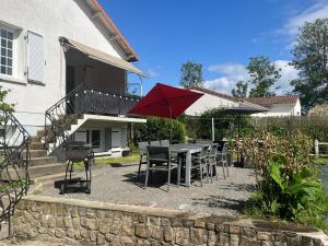 a patio with a table and chairs and a red umbrella at Logis de Bois Vert in Bressuire