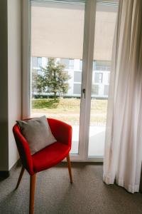 una sedia rossa seduta davanti a una finestra di SwissTech Hotel a Losanna Altre 24 foto