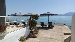 a patio with chairs and umbrellas next to the water at Christinas 3 in Nerántza