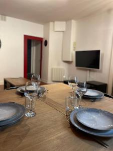 a wooden table with plates and wine glasses on it at Auron - 4 personnes - Hypercentre in Bourges