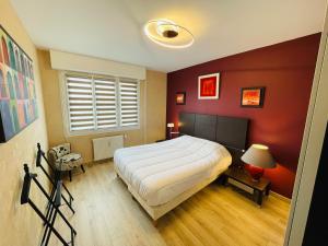 a bedroom with a bed and a red wall at Yucca, Appartement avec garage privé et balcon in Caen
