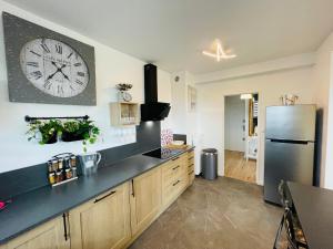 a kitchen with a large clock on the wall at Yucca, Appartement avec garage privé et balcon in Caen +11 photos
