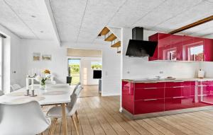 a kitchen with red cabinets and a white table at Cozy Home In Haderslev With Wifi in Haderslev