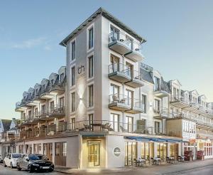 een gebouw met daarvoor geparkeerde auto's bij Baltic Hideaways Beach Hotel Warnemünde in Warnemünde