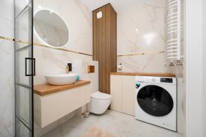 a bathroom with a washing machine and a sink at Widzewska Deluxe Apartment by BookingHost in Łódź