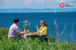 Un uomo e una donna seduti a un tavolo vicino all'oceano di La Maison de l'Échouerie on Chaleur Bay Seaside a Bonaventure