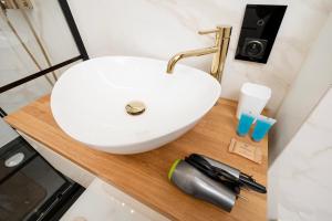 a white sink on a wooden counter in a bathroom at Widzewska Deluxe Apartment by BookingHost in Łódź +15 photos