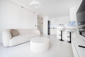 a white living room with a white couch and a table at Widzewska Deluxe Apartment by BookingHost in Łódź