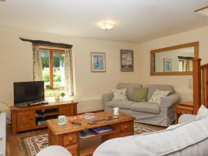 a living room with a couch and a tv at Peace Cottage in South Molton