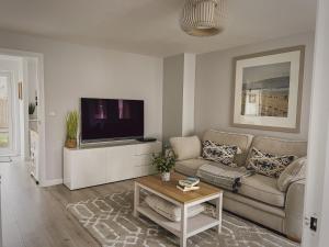 a living room with a couch and a tv at Sunnyside in Camber