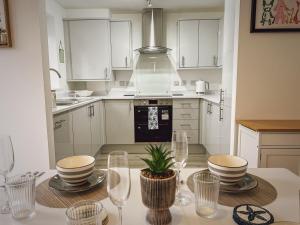 a kitchen with white cabinets and a table with wine glasses at Sunnyside in Camber