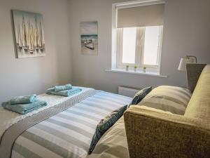 a bedroom with a bed and a couch and a window at Sunnyside in Camber