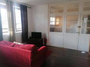 a living room with a red couch and a tv at Chez henry in Peyrat-le-Château