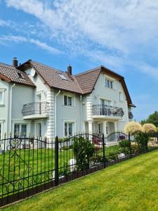 a white house with a black fence at WILLA RÓŻA WIATRÓW in Dziwnówek