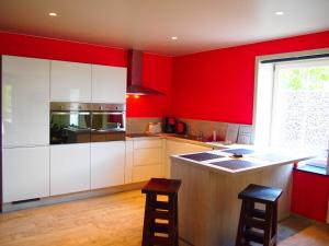 a kitchen with red walls and white cabinets at Archipel Holiday Cottage in Ellezelles