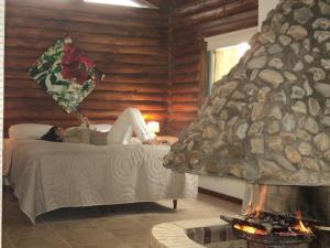 una mujer acostada en una cama junto a una chimenea en Cabañas El Secreto, en Monte Hermoso