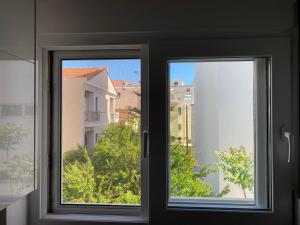 a window with a view of a building at A Modern & Homely 1BR Apartment in Chios