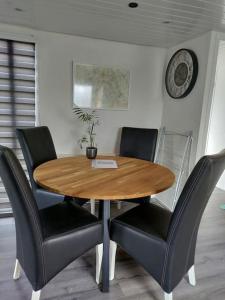 a dining room table with chairs and a clock on the wall at Chalet midden in de natuur! in Anloo +27 photos