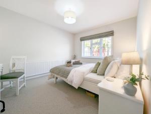 a white bedroom with a bed and a window at One Elms Way - Sleeps 6 - West Wittering in West Wittering