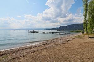a dock in the water next to a beach at Appartamento bellissima vista lago, spiaggia privata,nuovo in Bardolino