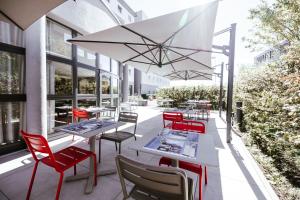 a patio with white tables and red chairs at Ibis Luxembourg Airport in Luxembourg