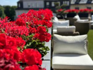 a bunch of red flowers sitting next to white chairs at Best Western Plus Thionville Centre in Thionville